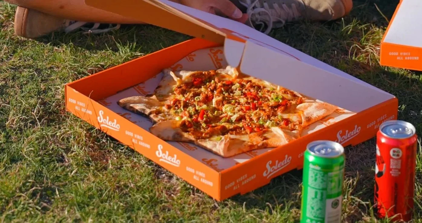 Soledo Pizza çekimi: çimenlerde açılmış Soledo pizza kutusu
